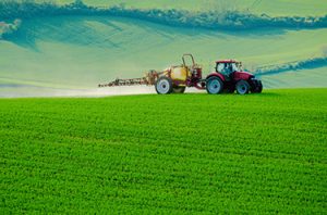 Tractor applying chemicals to green field